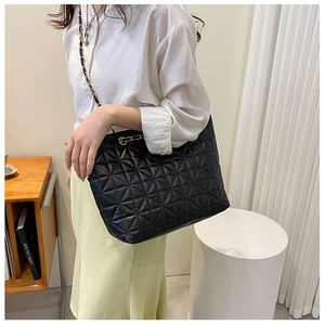 Detail of black quilted tote bag showing star pattern and gold chain woven shoulder strap