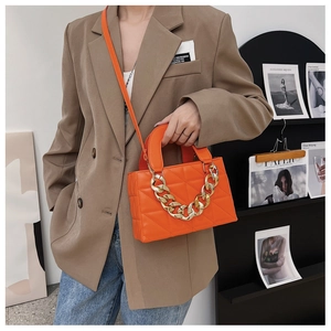 Détail du sac matelassé orange vif avec chaîne dorée épaisse et motif à losanges