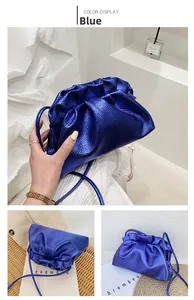 Detail of metallic blue pouch bag showing pleated texture and thin shoulder strap