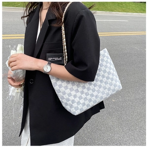 Detail of grey and white woven checkerboard tote bag with dual-tone metal chain strap