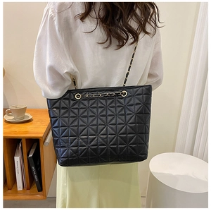 Detail of the black quilted tote bag showing starburst stitching and gold chain strap