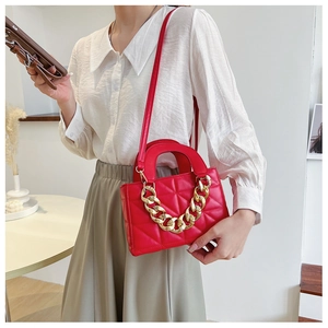 Détail du sac à main rouge matelassé avec chaîne dorée élégante et texture raffinée
