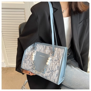 Detail of light blue pleated tote bag with pearl flower chain and fashion leather patch