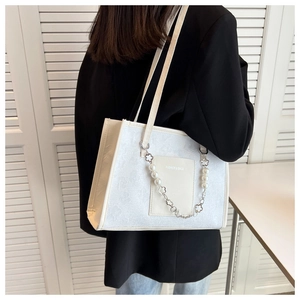 Detail of white embossed floral tote bag featuring pearl flower chain and fashion text