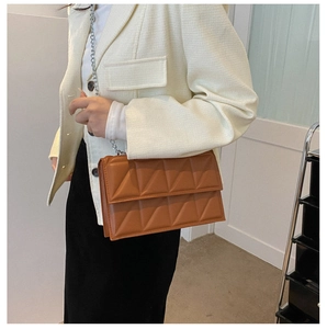 Detailed view of brown geometric quilted shoulder bag with silver chain strap on model