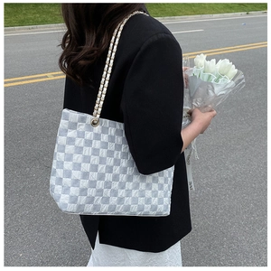 Close-up of checkered quilted tote bag featuring a premium metal chain shoulder strap