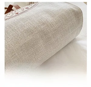 Close-up of woven canvas fabric texture with brown geometric embroidery and leather handle