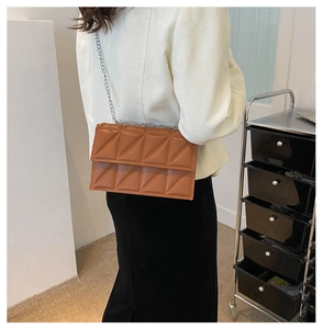 Brown crossbody box bag with geometric quilted pattern and silver chain strap on model