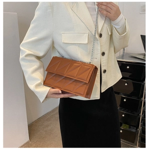 Caramel brown quilted crossbody box bag with silver chain strap shown on a model