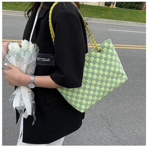 Detail of green checkerboard textured tote bag with gold chain woven shoulder strap