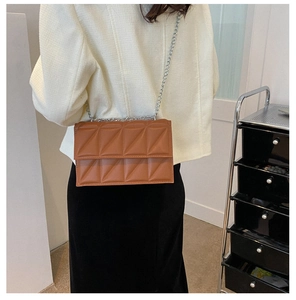Brown quilted square crossbody bag with silver chain strap shown on model shoulder