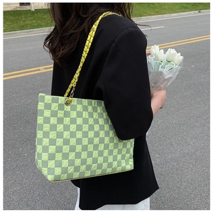 Detail of light green checkerboard tote bag with pleated texture and woven chain strap