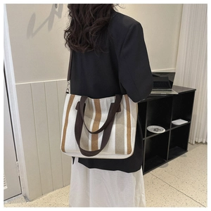 Detailed close-up of large canvas tote bag with brown vertical stripes and leather strap