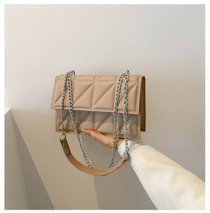 Detail of beige quilted flap bag showing geometric stitching and silver metal chain strap