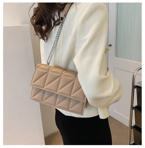 Model wearing a beige quilted chain crossbody bag with geometric stitching details