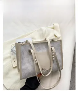 Detail of white floral textured tote bag featuring pearl chain and leather handle