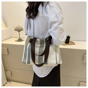 Lifestyle shot of large canvas tote bag with gray stripes on a beige background