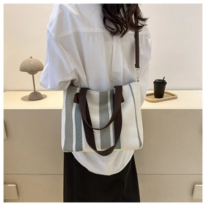 Lifestyle view of the striped canvas tote bag showing size and proportion on person