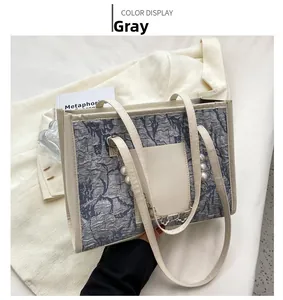 Detail of grey tote bag with marble pattern, pearl chain and metal flower charm detail