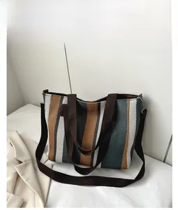 Detail view of striped canvas tote bag with reinforced handles and long shoulder strap