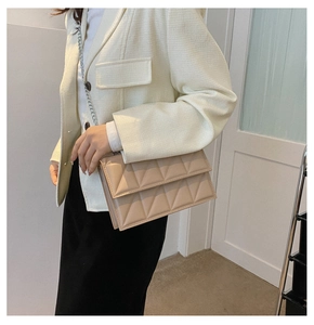 Quilted beige crossbody bag with silver chain strap shown on model in tweed jacket