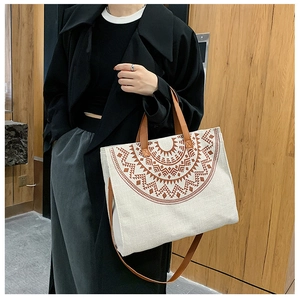 Canvas tote bag with geometric pattern featuring brown leather handles and shoulder strap