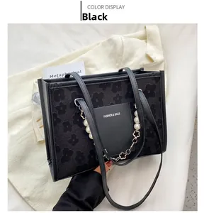 Macro detail of black floral jacquard tote bag with white pearl and metal flower chain