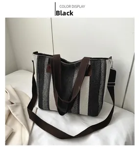 Detail of striped canvas tote bag showing black and white vertical pattern and brown strap