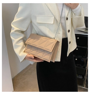 Detail of light beige quilted chain bag with geometric stitching on a crossbody model