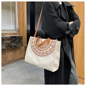 Close-up of cream canvas tote bag with brown geometric ethnic patterns and leather straps