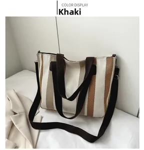 Detail view of the striped canvas tote bag with adjustable brown shoulder strap