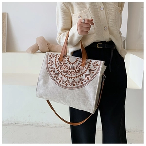 Detail of canvas tote bag with brown geometric print and leather shoulder strap