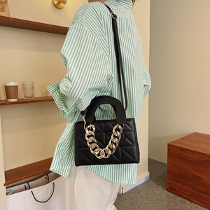 Sac à bandoulière matelassé noir chic avec chaîne dorée et poignée porté par un mannequin