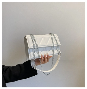 Close-up of a white quilted crossbody bag featuring silver chain and leather straps