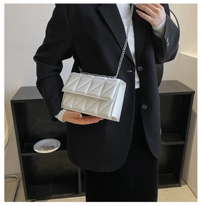 Close-up of white quilted leather crossbody bag with silver chain strap on model