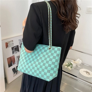 Fashionable mint green checkerboard tote bag with gold chain strap shown on model