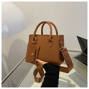 Brown tote bag with top handles, wide fabric strap, and matching small coin pouch detail