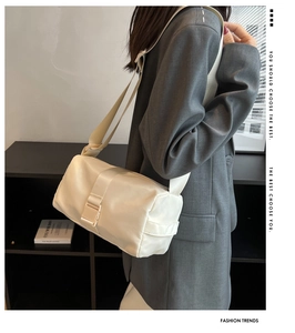 Dettaglio della borsa a tracolla in nylon crema con fibbia su una modella con blazer grigio