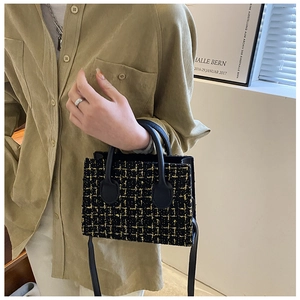 Detail of mini tweed handbag in black and gold with leather handle and shoulder strap