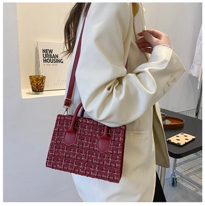 Detail of burgundy tweed handbag featuring gold-tone hardware and leather handle