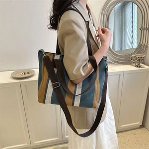 Striped canvas tote bag with adjustable shoulder strap shown on model for daily commuting