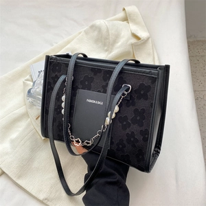 Fashionable black tote bag with floral embossing and decorative pearl chain accessory