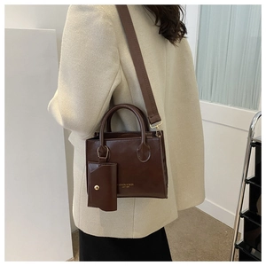 Detail of dark brown leather tote bag with small snap pouch and wide fabric strap