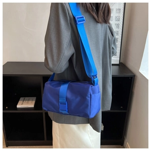 Nylon crossbody bag in bright blue featuring wide adjustable strap on a model