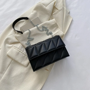 Quilted black geometric crossbody box bag with silver chain strap on elegant background