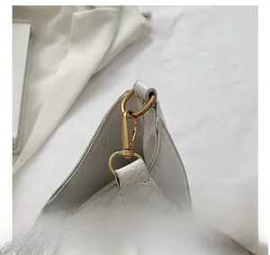Dettaglio del gancio dorato e della texture a coccodrillo della borsa bianca
