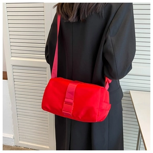 Dettaglio di borsa a tracolla in nylon rosso con fibbia rosa indossata da una modella