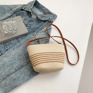 Detailed view of woven straw crossbody bag with brown stripes and leather strap