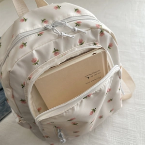 Detailed top view of a cream floral backpack with pink blossoms and dual zippers