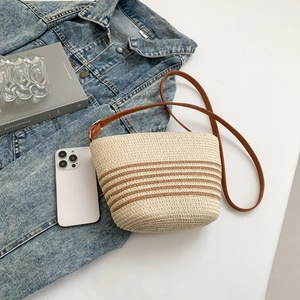 Macro shot of striped woven straw crossbody bag with adjustable leather shoulder strap